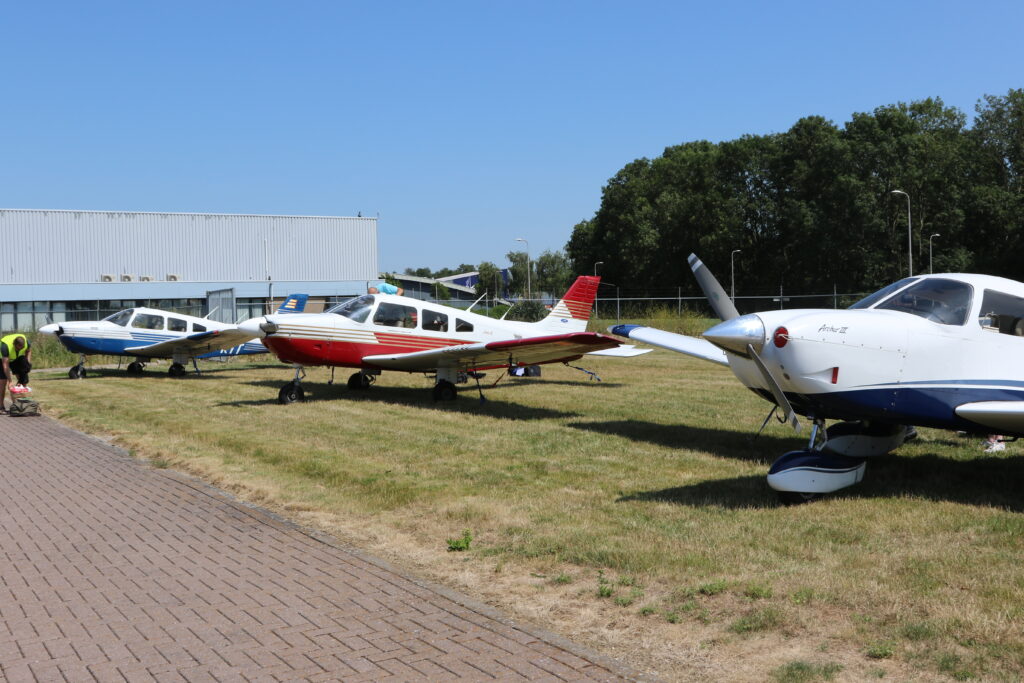 Tre enmotoriga propellerflygplan parkerade på en gräsplan och förankrade i marken.