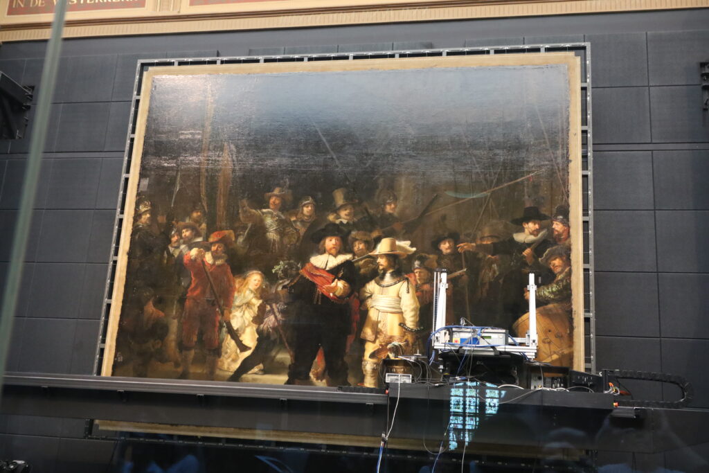 Foto av Rembrandts tavla "Nattvakten". Nederkanten av tavlan är blockerad av teknisk utrustning.