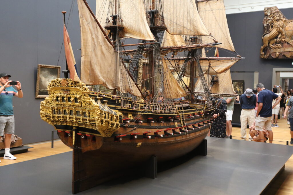 Foto av en modell av ett segelfartyg i en museiesal. Modellen tornar upp sig över människorna som står omkring den.