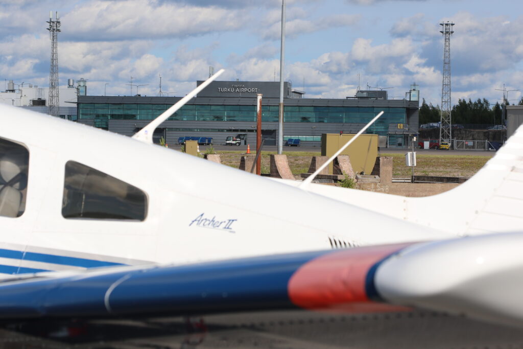 Terminalbyggnaden på Åbo/Turku flygplats, sedd över ryggen på en parkerad PA-28.